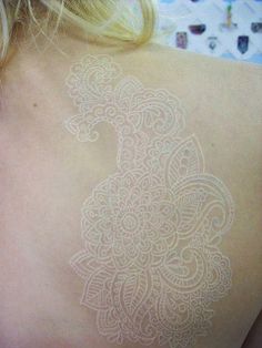 the back of a woman's shoulder with an intricate tattoo on it