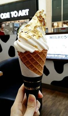 a hand holding an ice cream cone with gold foil