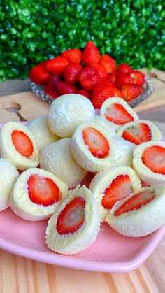 strawberries are arranged on a pink plate next to some cut - up doughnuts