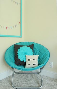 a chair with a pillow on it in front of a mirror and pictures hanging on the wall