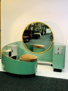 a round mirror sitting on top of a table next to a green bench and stool