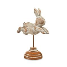 a white and brown statue of a rabbit on top of a wooden base with one leg up
