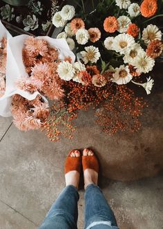 a person standing in front of flowers with their feet propped up on the ground next to them