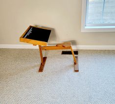 a small wooden table sitting on top of a carpeted floor next to a window