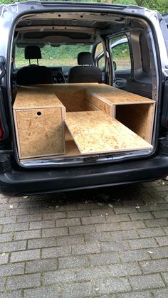 an open trunk in the back of a van with its doors open and some wooden boxes inside