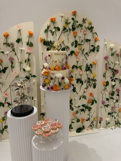 three white vases with flowers and cookies on them in front of a floral wall