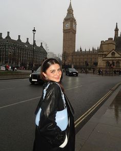 a woman is standing on the street in front of big ben