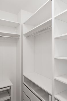an empty walk in closet with white shelving