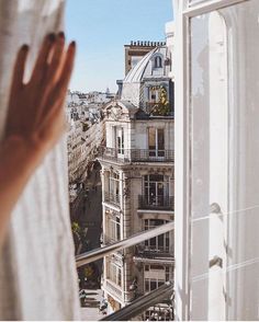 a woman looking out the window at buildings in paris, france with her hand up to her face