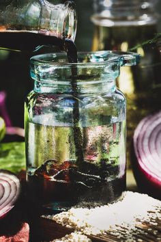 a jar filled with liquid sitting on top of a table next to sliced red onions