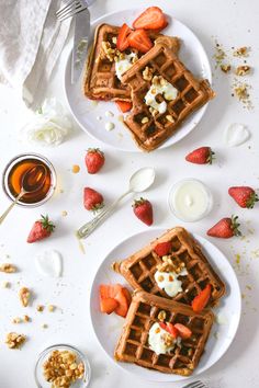 two plates with waffles and strawberries on them next to some honey syrup