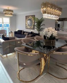a living room filled with lots of furniture and a chandelier above the table