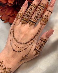 a woman's hand with henna tattoos on it and flowers in the background