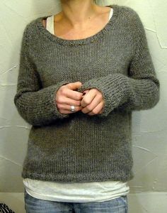 a woman standing in front of a wall with her hand on her hip and looking at the camera