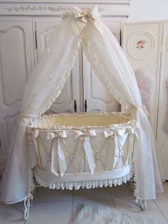 a baby crib with white curtains and bows on it