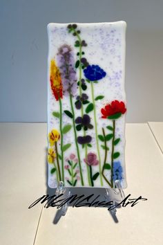 a glass plate with flowers painted on it sitting on a white counter top next to a knife holder