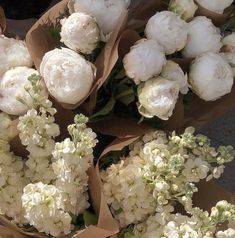bunches of white flowers sitting on top of brown paper wrapped in brown paper bags