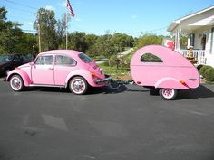 a pink car pulling a trailer in front of a house