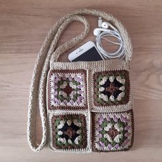 a crocheted purse with an ipod and earphones in it on a wooden surface