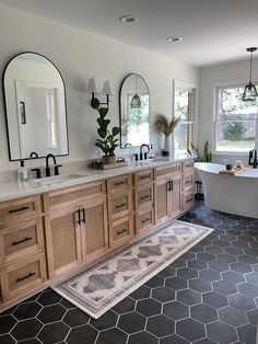 a bathroom with double sinks, mirrors and a bathtub in the middle of it