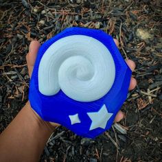 a hand holding a blue and white object with stars on it's side in the grass
