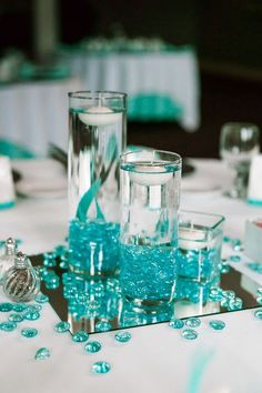 the centerpieces are filled with blue beads and glass vases, along with candles