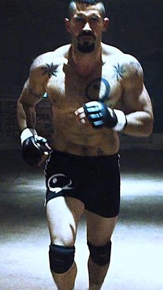 a shirtless man standing in front of a sign with tattoos on his arms and chest