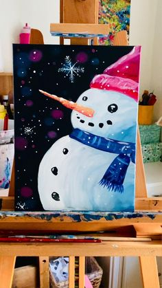 a painting of a snowman wearing a red hat and scarf on an easel