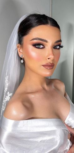 a woman in a wedding dress with a veil over her head and makeup on her face