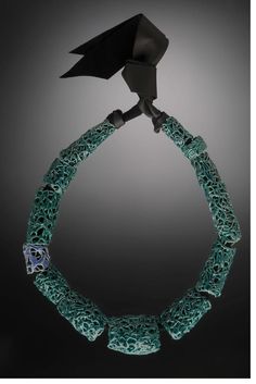 a necklace with green beads and a black bird on it's head, in the middle