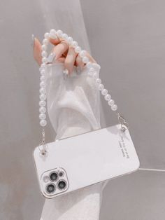 a woman's hand holding a white phone case with pearls on it
