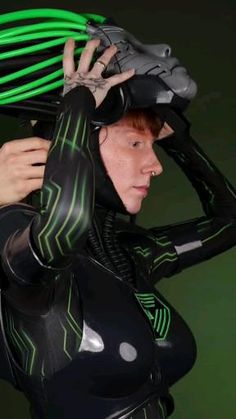 a woman dressed in black and green is holding her helmet