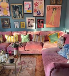 a living room filled with pink couches and pictures on the wall above them,