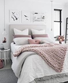a bed with white sheets and pink blankets