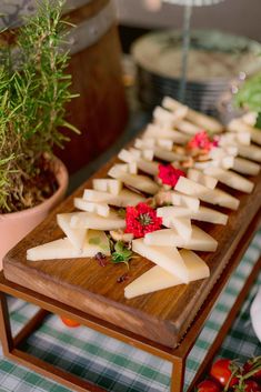 a wooden table topped with lots of cheese on top of a green and white checkered table cloth