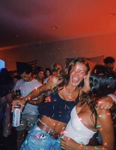 two women are dancing with confetti in front of them at a club or party