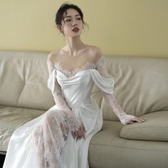 a woman sitting on top of a couch in a white dress