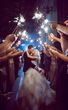 a bride and groom kissing while surrounded by sparklers