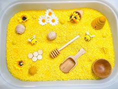 a plastic container filled with yellow food and wooden utensils on top of it