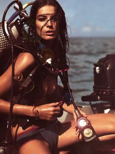 a woman sitting on the back of a boat with a scuba equipment in her hand