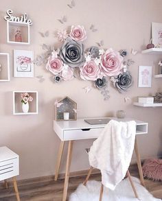 a white desk topped with a laptop computer next to a wall covered in pink and grey paper flowers