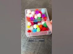 a person holding a container filled with colorful balls