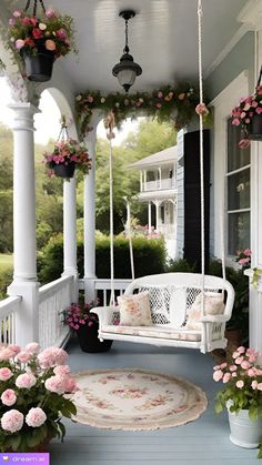 a white porch swing with pink flowers on it and potted plants hanging from the ceiling
