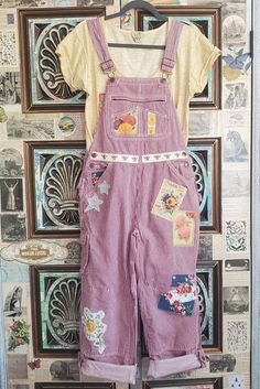 a child's overalls hanging up against a wall with pictures on the wall behind it