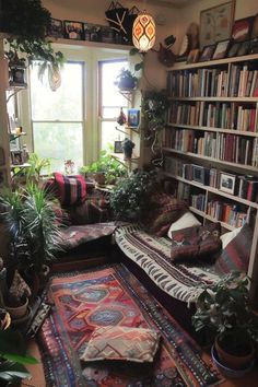a living room filled with lots of plants and bookshelves next to a window