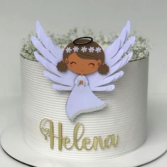 a white cake with an angel on top and name written on the side, in gold lettering