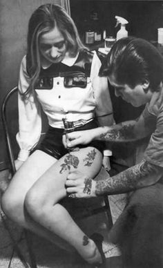 a man is getting his leg tattooed by a woman in a sailor's uniform