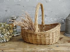 a wicker basket sitting on top of a wooden table next to some dried flowers