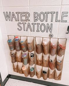there is a sign that says water bottle station with many cups on the wall behind it