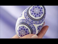 a hand is holding an egg decorated with blue and white designs on it's shell